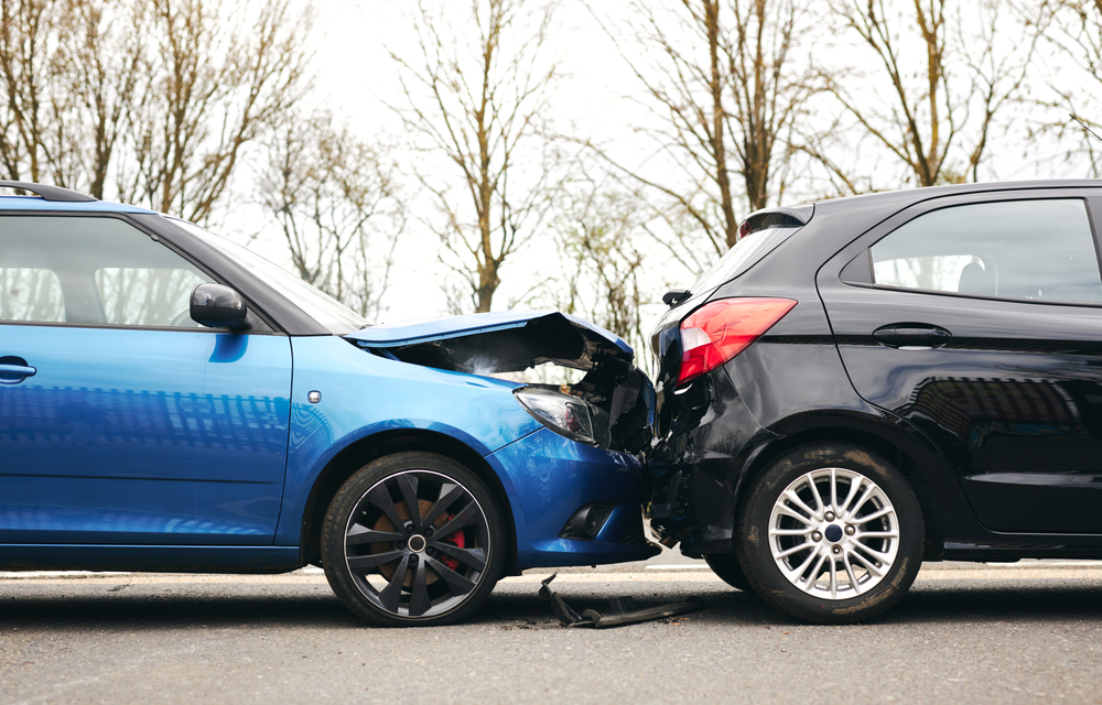 Two cars in a rear-end collision on the roadside, showing damage to the rear of one car and the front of the other