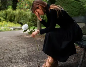 a woman sitting on a bench and holding a flower