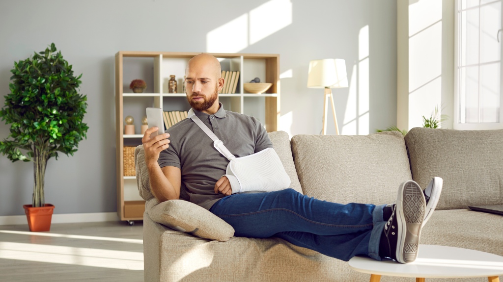 Man with broken arm using mobile phone