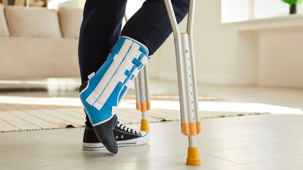 man walking with crutches in ankle brace with support adjustable strap fracture fixator