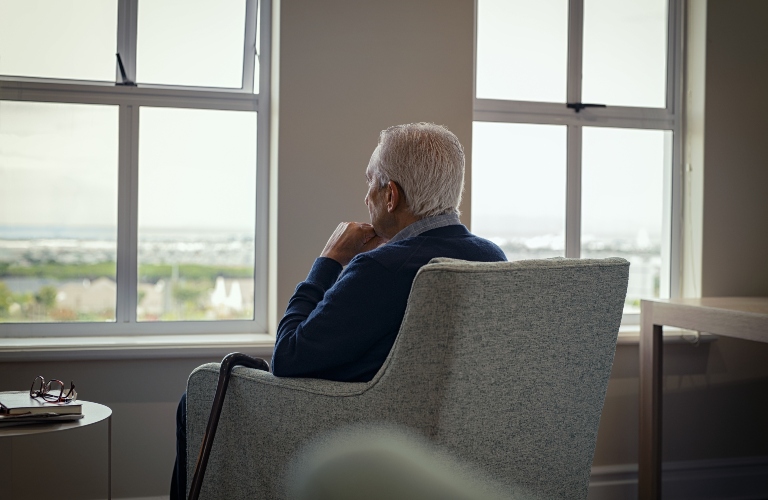 senior man sitting on armchair and looking through the window