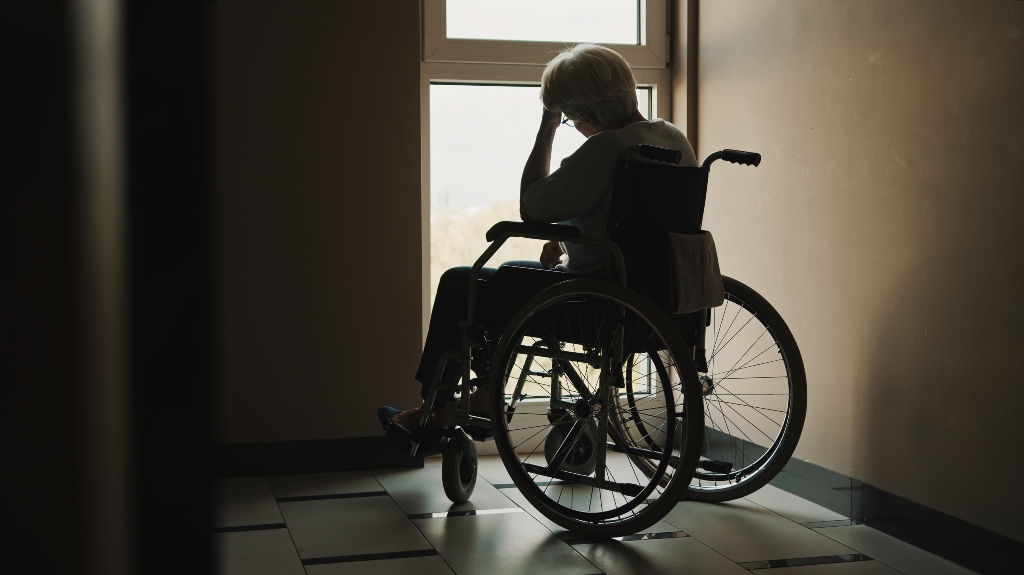 senior woman looking through the window of the nursing home