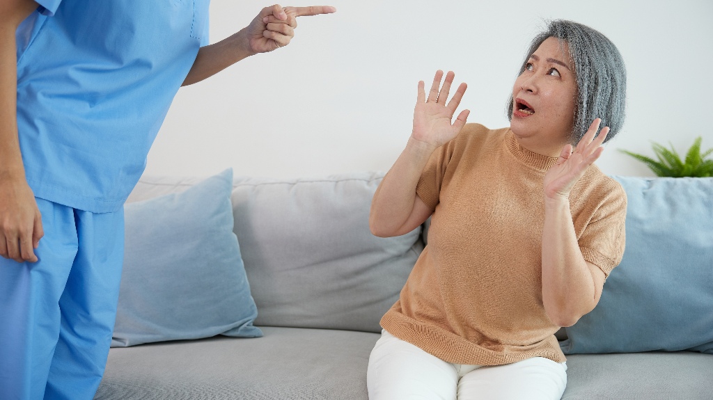 angry caregiver blaming or mistreating senior woman