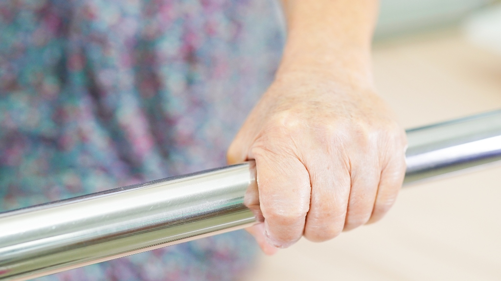 senior woman patient holding bed rail